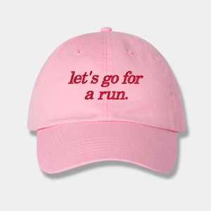 May include: Pink baseball cap with the text "let's go for a run." embroidered in red.