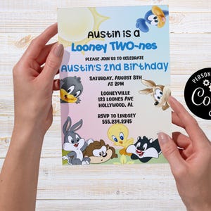 以下が含まれることがあります： オースティンの2歳の誕生日を祝う、ルーニー・テューンズのキャラクターが登場するカラフルな招待状。「Austin is a Looney TWO-nes」というテキストとイベントの詳細が含まれています。デザインには太陽と様々な漫画のキャラクターが使用されています。