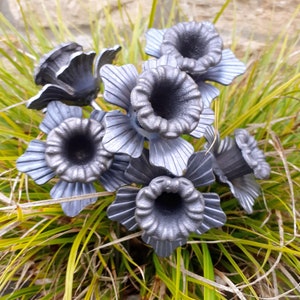 Puede incluir: Un grupo de narcisos de metal en acabado gris. Las flores est&aacute;n dispuestas en un ramo y tienen un aspecto realista.