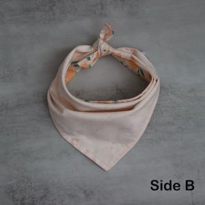 May include: A pink bandana with a floral pattern on one side and a subtle pattern on the other side. The bandana is tied in a knot at the top. The text "Side B" is visible at the bottom of the image.