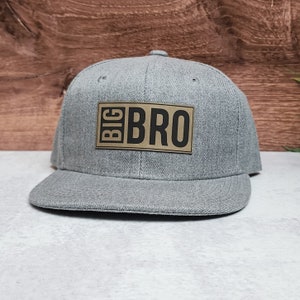 May include: Gray baseball cap with a brown patch that says "BIG BRO" in black letters.