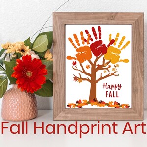 May include: A framed print of a handprint tree with orange, red, and yellow handprints. The tree has a brown trunk and branches. The text "Happy FALL" is written below the tree. The print is on a white background and is framed in a light brown frame.