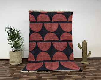 Könnte beinhalten: Ein roter und schwarzer geometrischer Teppich mit einem Muster aus Halbkreisen. Der Teppich hat einen Fransenrand.