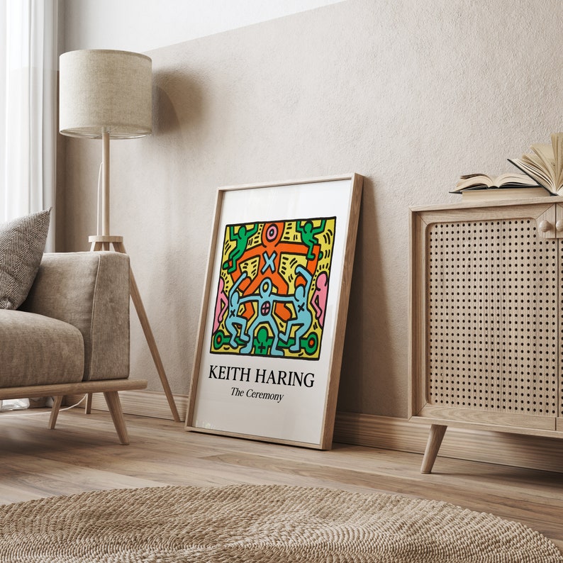 May include: A framed print of a colorful Keith Haring artwork titled "The Ceremony". The artwork features a group of stick figures in a circle, with a central figure holding a cross.
