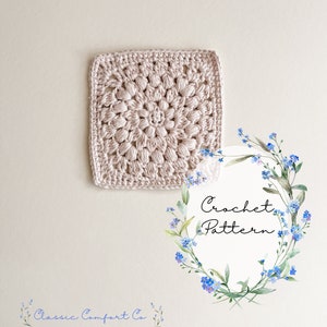 May include: A crochet pattern for a square granny square with a floral design in a light pink color. The pattern is surrounded by a watercolor wreath of forget-me-not flowers. The text "Crochet Pattern" is written in black on a white background inside the wreath.