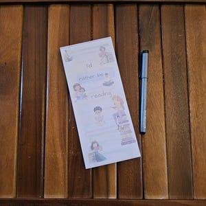 May include: A set of four colorful bookmarks with illustrations of people reading books. The bookmarks have the text "I'd rather be reading" on them.