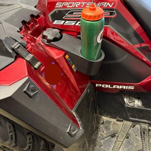 May include: A red and black Polaris Sportsman 850 ATV with a green and orange Gatorade water bottle in the cup holder. The ATV has the word "Sportsman" and "850" printed on the side.