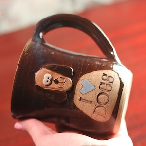 May include: Brown ceramic coffee mug with a dog face and the words "I love dogs" on the side.
