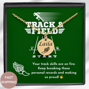 May include: A gold necklace with a round pendant that says "Laila" and has a running shoe with wings on it. The necklace is in a green box with the words "TRACK & FIELD" on it. The box also has a running shoe with wings on it and the words "START" and "1" and "5" on it. The text on the box also says "Your track skills are on fire. Keep breaking those personal records and making us proud!"