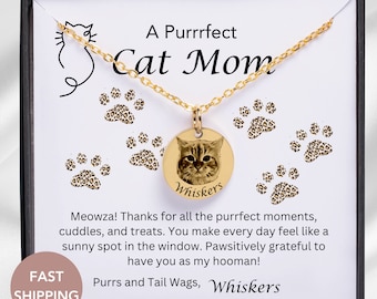 May include: A gold necklace with a round pendant featuring a cat's face and the name "Whiskers". The pendant is surrounded by paw prints with a leopard print design. The necklace comes in a box with a message that reads "A Purrrfect Cat Mom".