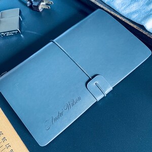May include: A blue leather-bound journal with the name "Andie Wilson" embossed in silver lettering.