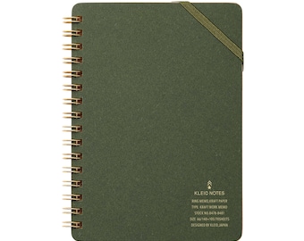 May include: A green spiral-bound notebook with gold-colored metal rings and an elastic band closure. The notebook has the text "KLEID NOTES" and other details printed on the bottom right corner. The notebook is A6 size and contains 70 sheets.