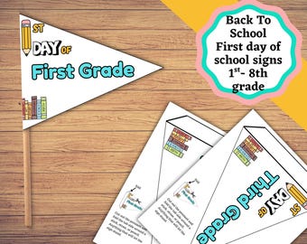 May include: A triangular pennant sign for the first day of first grade featuring a yellow pencil illustration, a stack of colorful books, and the text "1st DAY OF First Grade" attached to a wooden stick, alongside printed instruction sheets.