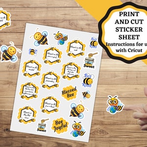 May include: A printable sticker sheet with bee-themed designs. The sheet features various bee illustrations, including a bee with glasses holding a globe, a bee with a honey pot, and a bee with a honeycomb. The sheet also includes text such as "Blessed Bee", "Bee Kind", and "Bee Joyful".