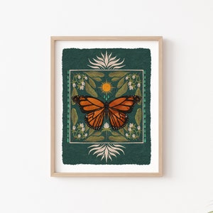 K&ouml;nnte beinhalten: Ein gerahmter Druck mit gr&uuml;nem Hintergrund, der einen stilisierten orangefarbenen und schwarzen Schmetterling mit einer Sonne und floralen Designs zeigt.
