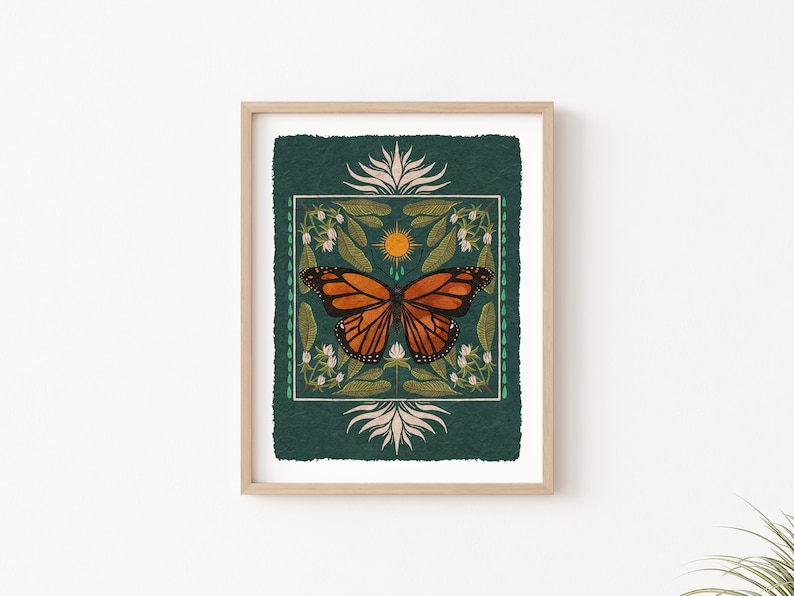 K&ouml;nnte beinhalten: Ein gerahmter Druck mit gr&uuml;nem Hintergrund, der einen stilisierten orangefarbenen und schwarzen Schmetterling mit einer Sonne und floralen Designs zeigt.