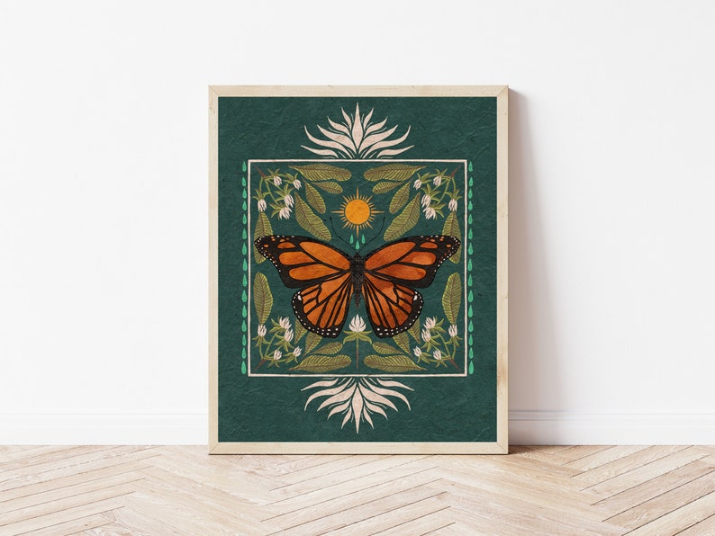 K&ouml;nnte beinhalten: Ein quadratischer Druck mit einem blaugr&uuml;nen Hintergrund, der einen Monarchfalter mit orangefarbenen und schwarzen Fl&uuml;geln, eine gelbe Sonne und wei&szlig;e Blumen zeigt. Der Schmetterling ist von einem gr&uuml;nen und wei&szlig;en Rand umgeben.