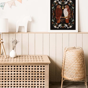 May include: A framed print with a black background featuring two red-tailed hawks perched on a branch with a floral and botanical design. The print is surrounded by a white frame.