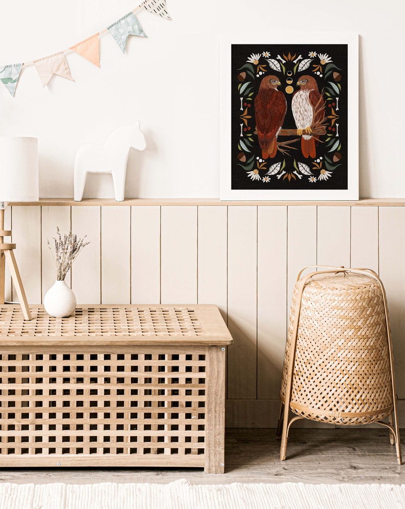 May include: A framed print with a black background featuring two red-tailed hawks perched on a branch with a floral and botanical design. The print is surrounded by a white frame.