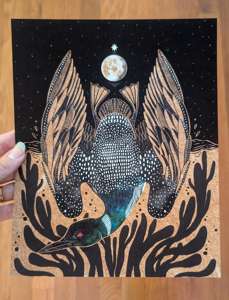 May include: A rectangular art print featuring a black and metallic gold illustration of a loon with wings spread wide. The bird has a white-spotted back, a dark head with a red eye, and is positioned below a moon and a star against a black sky.