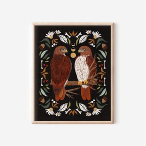 May include: Two red-tailed hawks perched on a branch, surrounded by a border of leaves, flowers, and other natural elements on a black background.