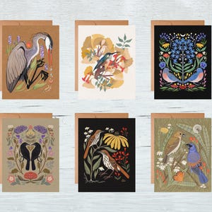 May include: A set of six greeting cards featuring colorful illustrations of birds and floral designs. Each card has a unique design, including a heron, bluebirds, and other birds. The cards are on a kraft paper background.
