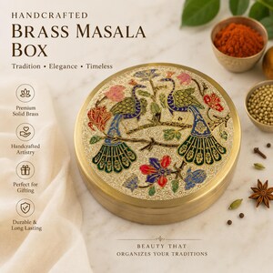 Op de afbeelding: Een ronde masala-doos van messing met een ingewikkeld gegraveerd ontwerp op het deksel, met twee pauwen op een tak omringd door bloemmotieven in blauwe, groene, rode en gouden tinten. De container heeft een gladde, metalen afwerking.