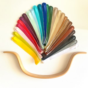 Może przedstawiać: Wiatrak złożony z 20 pasków skórzanych w różnych kolorach, w tym żółtym, czerwonym, zielonym, niebieskim, brązowym i białym. Paski są ułożone w półkole, z końcami skierowanymi do środka. Paski mają tę samą długość i szerokość. Paski są ułożone w kształcie wiatraka, z końcami skierowanymi do środka. Paski mają tę samą długość i szerokość.