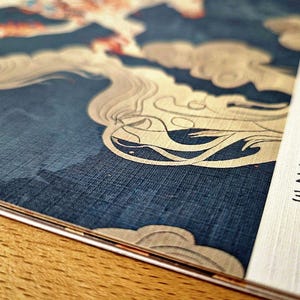 May include: Close-up of a calendar with a decorative blue and cream design. The design features a stylized cloud pattern. The calendar pages are white with black text, showing the days of the month.