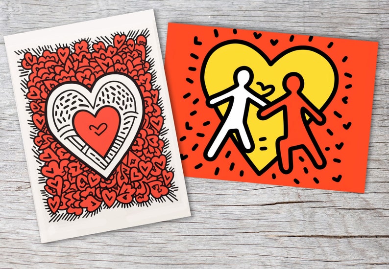 Puede incluir: Dos impresiones art&iacute;sticas con dise&ntilde;os de coraz&oacute;n. Una presenta un gran coraz&oacute;n lleno de corazones m&aacute;s peque&ntilde;os, y la otra muestra dos figuras tomadas de la mano dentro de un coraz&oacute;n amarillo sobre un fondo rojo. Ambas est&aacute;n sobre una superficie de madera.