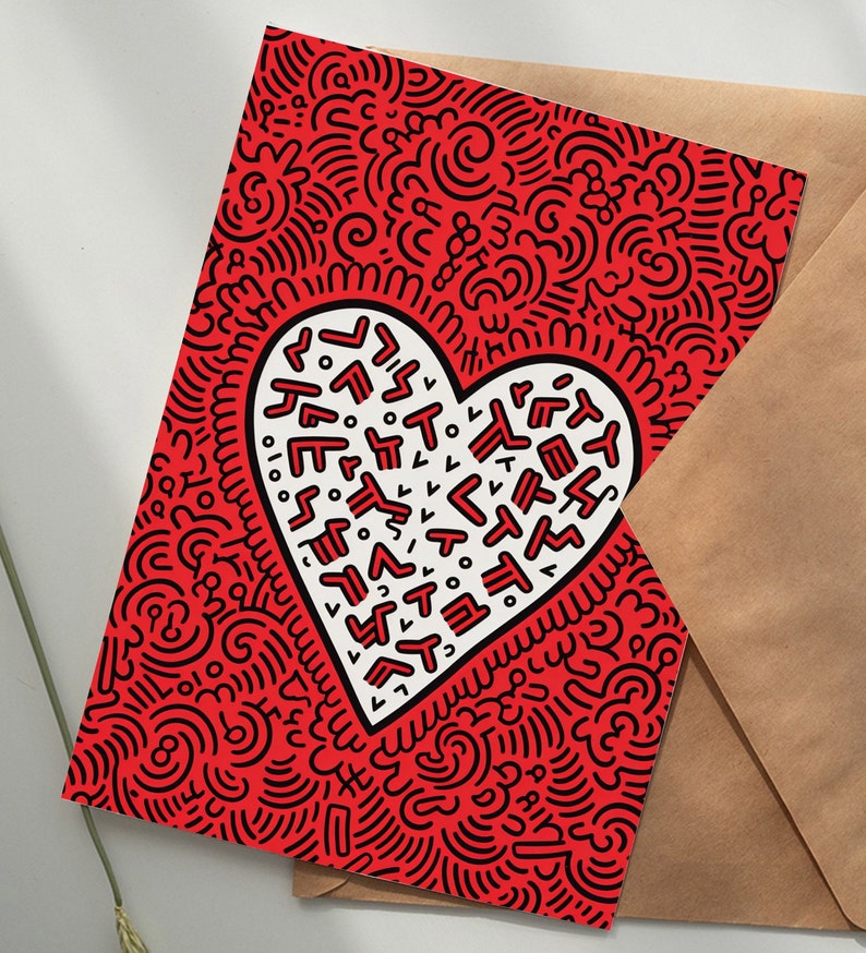 Puede incluir: Tarjeta de felicitaci&oacute;n roja con un dise&ntilde;o en forma de coraz&oacute;n blanco lleno de formas y texto abstractos. La tarjeta tiene un fondo de patr&oacute;n de garabatos negro y va acompa&ntilde;ada de un sobre marr&oacute;n. Adecuada para diversas ocasiones.