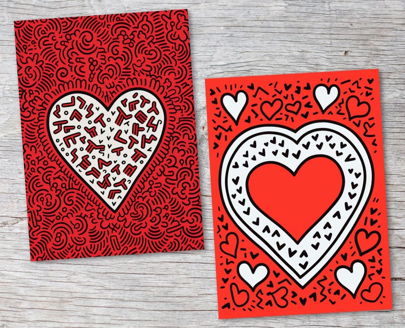 Puede incluir: Dos tarjetas de felicitaci&oacute;n rojas con dise&ntilde;os de coraz&oacute;n. Una tarjeta presenta un gran coraz&oacute;n blanco lleno de formas negras sobre un fondo rojo. La otra tarjeta tiene un coraz&oacute;n rojo con un borde blanco y corazones blancos m&aacute;s peque&ntilde;os.