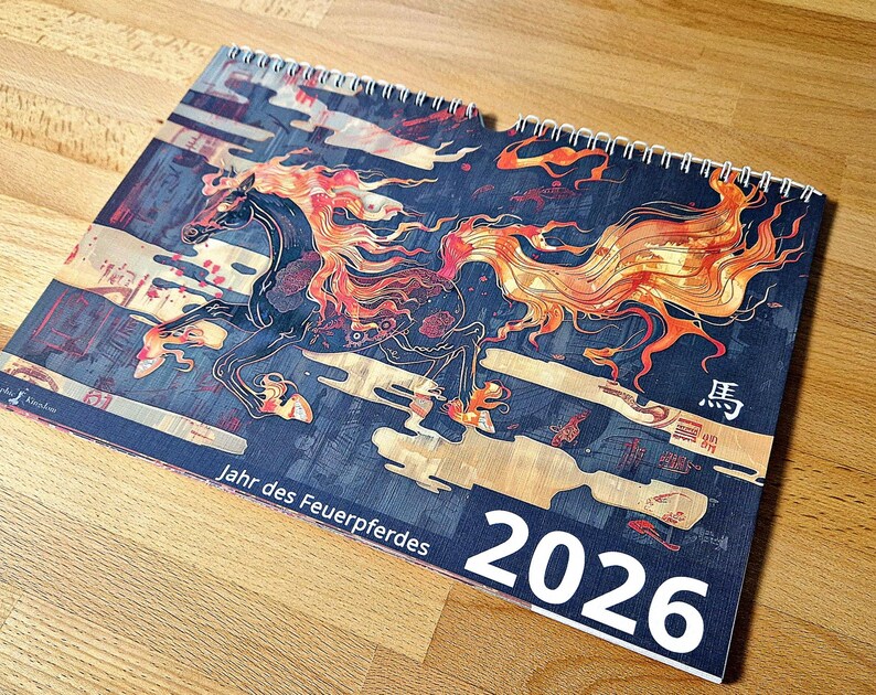 May include: A spiral-bound calendar for 2026 featuring a stylized illustration of a running horse with fiery orange and red mane and tail. The calendar has a dark blue background with Japanese text and the words "Jahr des Feuerpferdes".