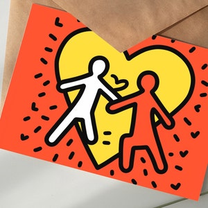 Puede incluir: Tarjeta de felicitaci&oacute;n con una ilustraci&oacute;n estilizada de dos figuras abraz&aacute;ndose dentro de un coraz&oacute;n amarillo sobre un fondo naranja. Las figuras est&aacute;n delineadas en negro, una blanca y otra naranja. La tarjeta est&aacute; sobre una superficie blanca.
