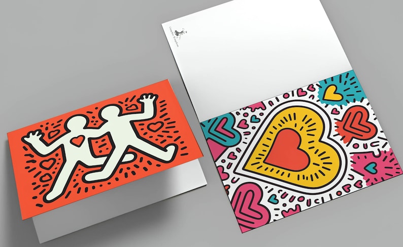 Puede incluir: Dos tarjetas de felicitaci&oacute;n con dise&ntilde;os coloridos. Una tarjeta presenta dos figuras blancas con un coraz&oacute;n sobre un fondo naranja. La otra tarjeta tiene un gran coraz&oacute;n con contorno amarillo y centro rojo, rodeado de corazones y acentos coloridos.