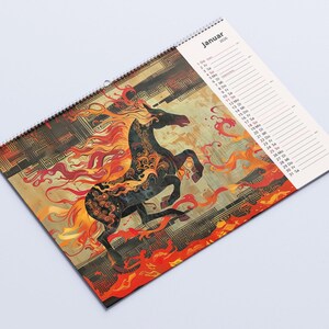 May include: A spiral-bound calendar featuring a stylized black horse with fiery red and orange mane and tail. The horse is set against a background of gold and brown geometric patterns. The calendar is labeled "Januar 2026".