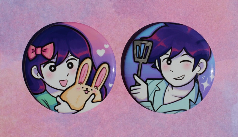 May include: Two round button badges featuring cartoon characters. The first badge depicts a girl with purple hair and a pink bow holding a yellow bunny. The second badge shows a boy with purple hair and a blue shirt holding a spatula.