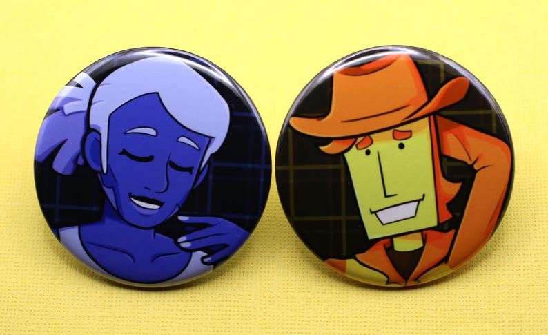 K&ouml;nnte beinhalten: Zwei runde Ansteckbuttons mit illustrierten Charakteren. Der linke Button zeigt eine blauh&auml;utige Figur mit hellem Haar und geschlossenen Augen. Der rechte Button zeigt eine gelbh&auml;utige Figur, die einen orangefarbenen Hut und ein Hemd tr&auml;gt.