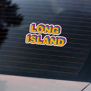May include: A silver car with a sticker on the back window that says "LONG ISLAND" in rainbow colors.