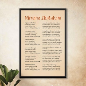 May include: A framed print of a Sanskrit text, "Nirvana Shatakam", in a traditional Indian script. The text is written in brown ink on a cream-colored background. The frame is black with a gold border.