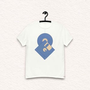 Puede incluir: Una camiseta blanca con un disquete azul y un disco de vinilo azul impresos en la parte delantera.