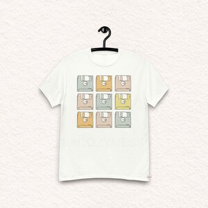 Puede incluir: Camiseta blanca con un diseño retro de nueve disquetes de colores.
