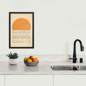 Ralph Waldo Emerson's Poster featuring  inspirational quote, Write it on your heart..., with a warm sun illustration, displayed in a black frame, on a kitchen wall.