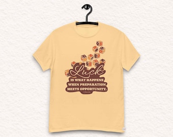 May include: A yellow t-shirt with a graphic of dice and the text "Luck is what happens when preparation meets opportunity."