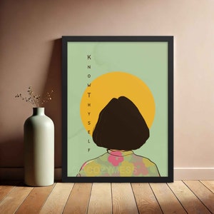 Puede incluir: Una impresión enmarcada con un fondo verde y un círculo amarillo detrás de una silueta de una persona con cabello castaño. El texto "KNOW THYSELF" está escrito verticalmente en el lado izquierdo de la imagen.