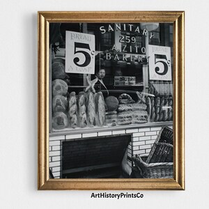 Puede incluir: Impresión enmarcada en blanco y negro de un escaparate de panadería. El escaparate muestra hogazas de pan y un letrero que dice "Bread 5 a loaf". El nombre de la panadería, "A. Zito Bakery", es visible encima del escaparate.