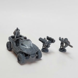 Könnte beinhalten: Ein graues Spielzeugfahrzeug aus Kunststoff mit einer Figur oben, zwei graue Spielzeugwaffen aus Kunststoff mit Figuren und einer grauen Kunststoffbasis.