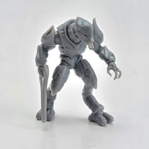 Op de afbeelding: Grijze plastic actionfiguur van een Halo Elite met een groot energiezwaard. De figuur staat in een vechtpose met één been naar voren en het andere been naar achteren.
