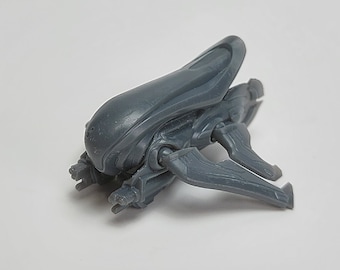 Könnte beinhalten: Ein graues Plastikmodell eines Covenant Banshee Raumschiffs aus der Halo-Videospielserie. Die Banshee ist ein kleines, wendiges Kampfschiff mit einem charakteristischen, geschwungenen Design.