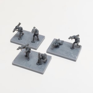 Könnte beinhalten: Fünf graue Plastik-Miniaturfiguren von Soldaten, die jeweils eine Waffe halten und auf grauen quadratischen Sockeln stehen.
